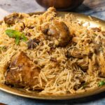 Close-up of aromatic chicken biryani served on a brass plate with garnishes, showcasing Indian culinary art.